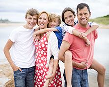 Happy parents with 3 smiling children by the beach