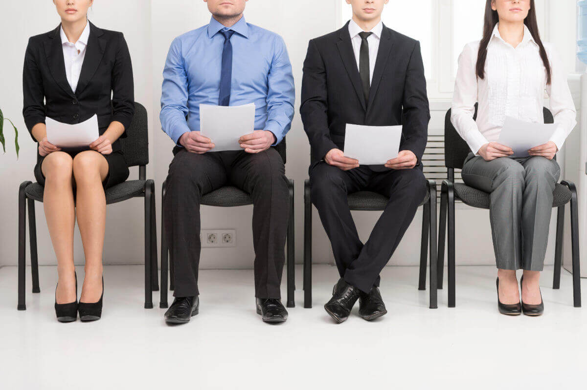 4 people sitting in a lobby holding papers waiting for interviews